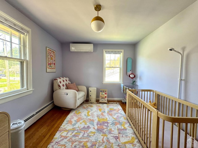 bedroom with a wall mounted air conditioner, a crib, baseboards, baseboard heating, and dark wood-style floors