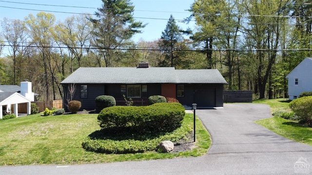 single story home featuring an attached garage, a chimney, fence, a front yard, and driveway