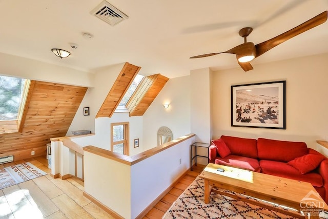 interior space featuring a wealth of natural light, wooden walls, ceiling fan, and light hardwood / wood-style floors