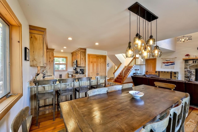 dining room with a chandelier, light hardwood / wood-style floors, and a stone fireplace