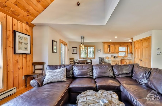 living room featuring hardwood / wood-style floors, sink, a baseboard heating unit, and wood walls