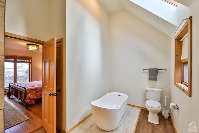 bathroom featuring vaulted ceiling with skylight, a bathtub, toilet, and wood-type flooring