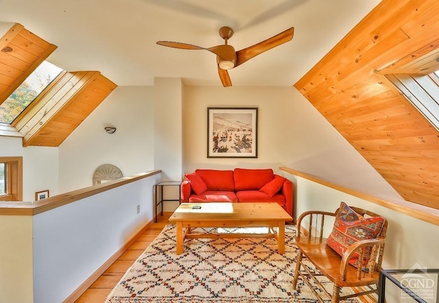 sitting room with ceiling fan, light hardwood / wood-style flooring, and vaulted ceiling with skylight