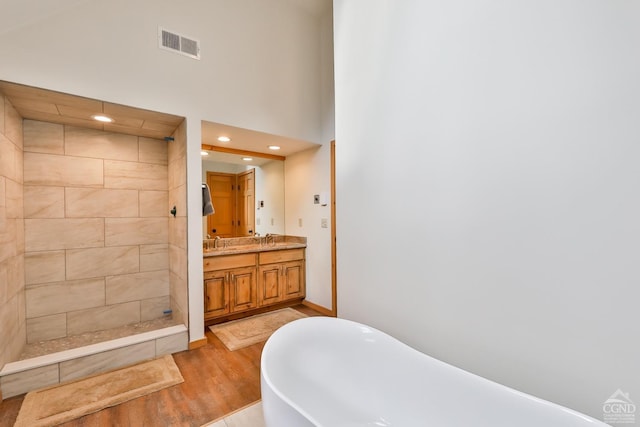 bathroom with separate shower and tub, vanity, wood-type flooring, and a high ceiling