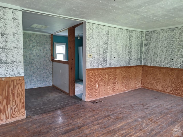 unfurnished room with wood walls, dark hardwood / wood-style flooring, and a textured ceiling