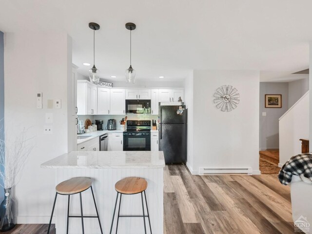 living room with a wall mounted AC, light hardwood / wood-style floors, and ceiling fan with notable chandelier