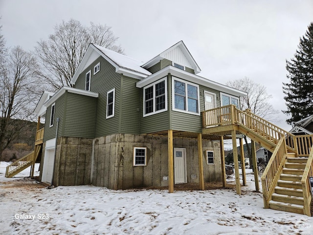 snow covered property featuring a garage and a deck