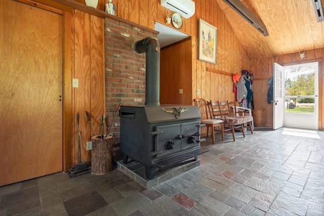 living room featuring wooden walls, a wood stove, a wall unit AC, and vaulted ceiling