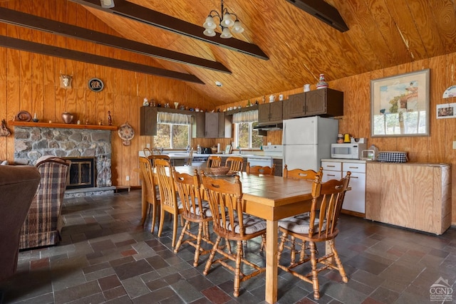 dining area featuring a stone fireplace, wood walls, wooden ceiling, and an inviting chandelier