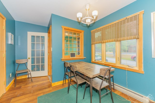 dining area with hardwood / wood-style flooring, a notable chandelier, and a baseboard heating unit