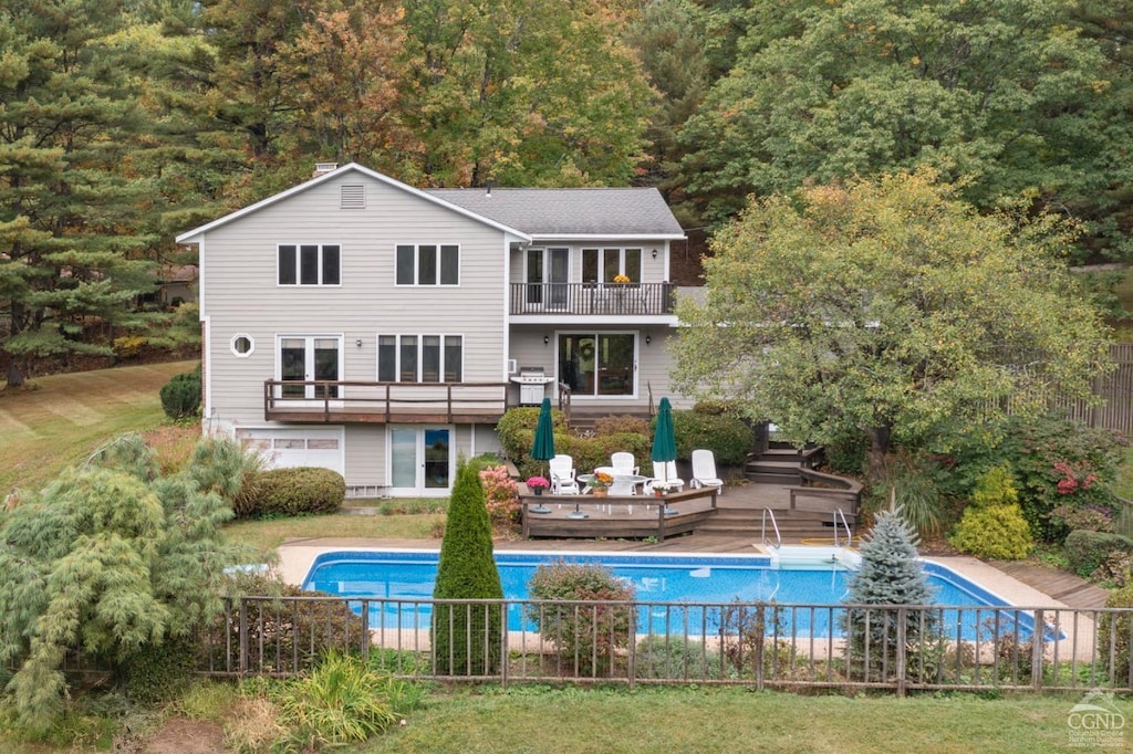 rear view of property with a pool side deck, a balcony, and a yard