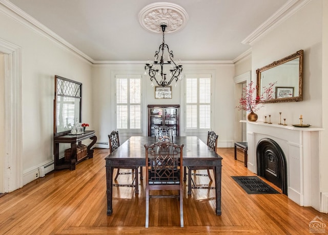 dining area with light hardwood / wood-style floors, a baseboard radiator, crown molding, and a notable chandelier