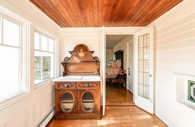 clothes washing area featuring light hardwood / wood-style floors, washing machine and dryer, wooden ceiling, and a baseboard radiator