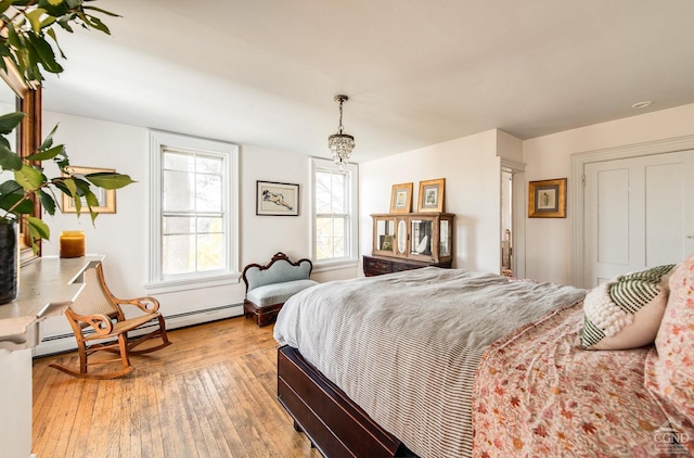 bedroom with light hardwood / wood-style flooring and a baseboard heating unit