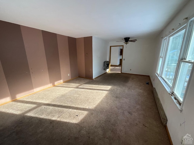 carpeted spare room with heating unit, baseboard heating, and ceiling fan