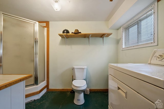 bathroom with vanity, baseboards, toilet, a shower stall, and washer / dryer