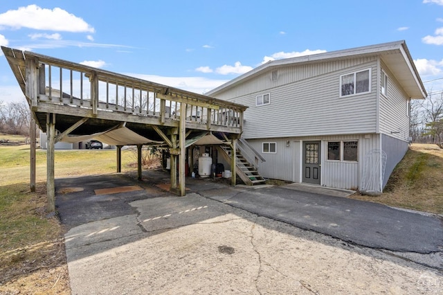 back of property with a carport, aphalt driveway, a deck, and stairs