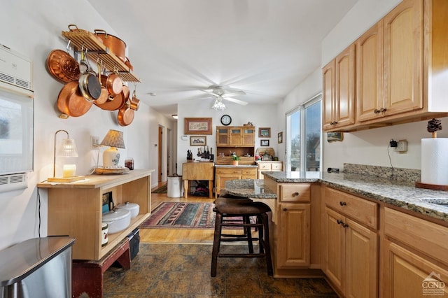 kitchen with a kitchen breakfast bar, light stone counters, a peninsula, stone finish floor, and ceiling fan