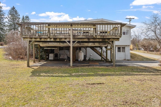 rear view of house featuring a carport, stairs, a deck, and a lawn
