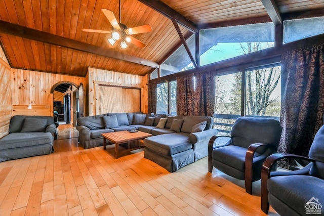 living room featuring a wealth of natural light, wooden walls, beamed ceiling, and light hardwood / wood-style flooring