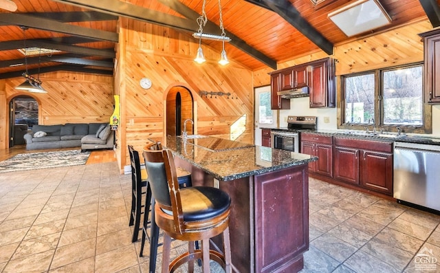 kitchen with hanging light fixtures, stainless steel appliances, an island with sink, a breakfast bar, and wood ceiling