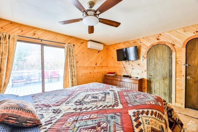 bedroom featuring access to outside, an AC wall unit, ceiling fan, and wood walls