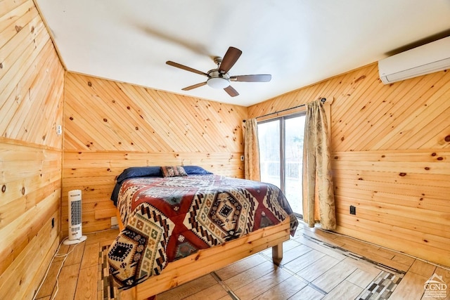 bedroom with a wall mounted AC, wood-type flooring, ceiling fan, and wooden walls