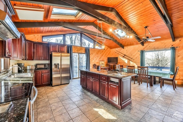 kitchen with stainless steel fridge, a center island, a wealth of natural light, and wood walls