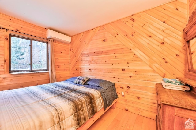 bedroom with light wood-type flooring, an AC wall unit, and wood walls