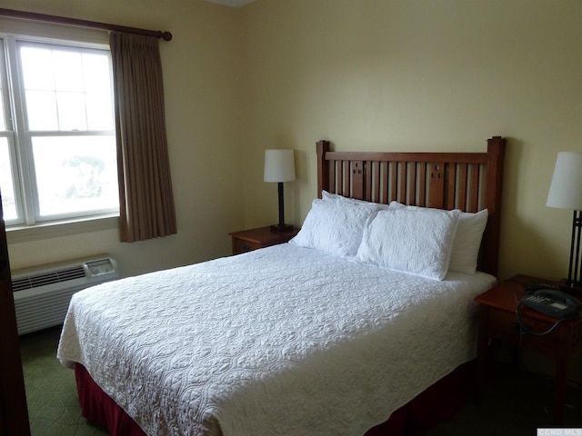 carpeted bedroom featuring an AC wall unit and multiple windows