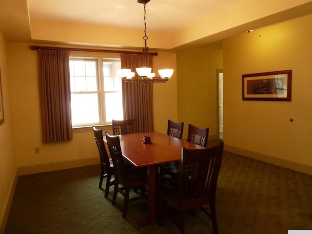 dining room featuring dark colored carpet, a raised ceiling, and an inviting chandelier