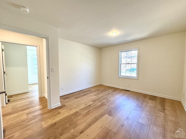 unfurnished room with baseboards, visible vents, and hardwood / wood-style floors