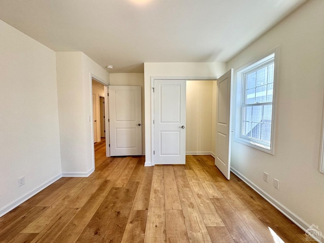 unfurnished bedroom with baseboards, light wood finished floors, and a closet