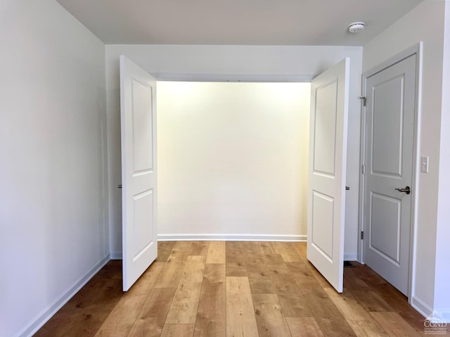 hallway featuring light wood-type flooring and baseboards