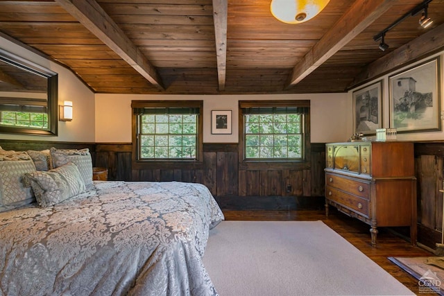 bedroom with wood walls, wooden ceiling, dark wood-type flooring, track lighting, and beam ceiling