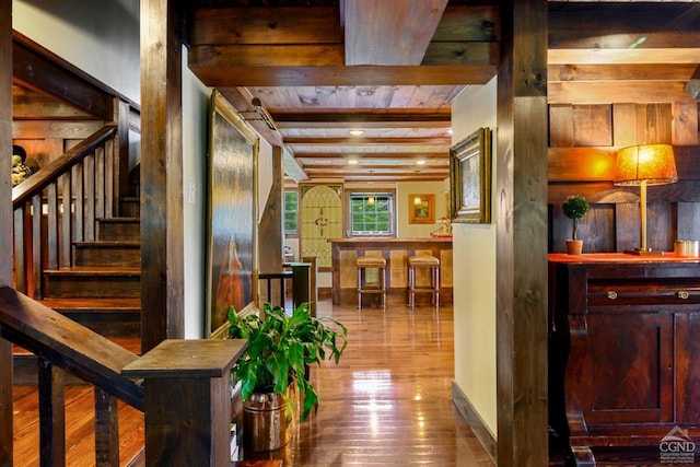 corridor with hardwood / wood-style floors, wooden ceiling, and beamed ceiling