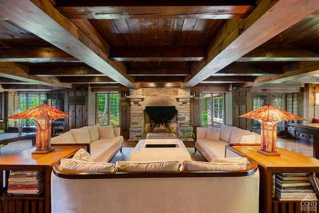 living room with a stone fireplace, beamed ceiling, and wood ceiling