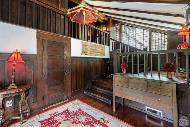 interior space featuring wood-type flooring, lofted ceiling with beams, and wooden walls