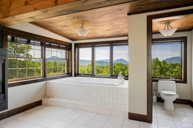 bathroom featuring a mountain view, lofted ceiling, tile patterned flooring, toilet, and tiled bath