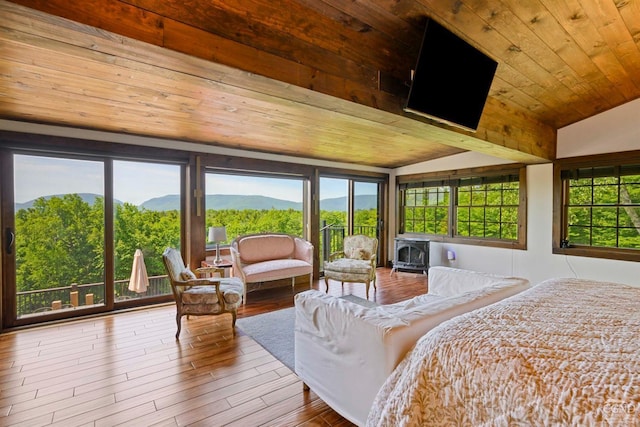 bedroom featuring a wood stove, wood-type flooring, vaulted ceiling, and wooden ceiling