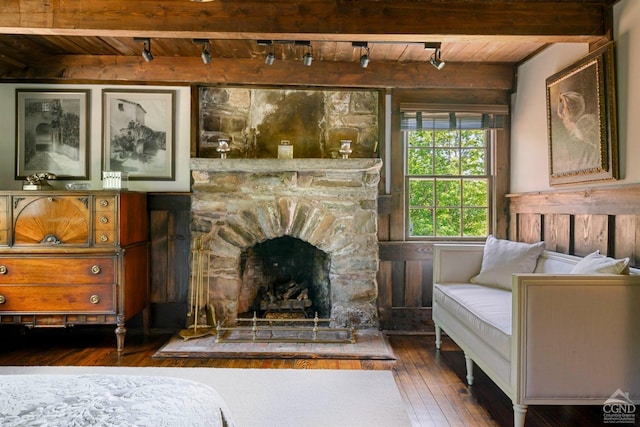 living area featuring beam ceiling, a stone fireplace, dark hardwood / wood-style flooring, and wood ceiling