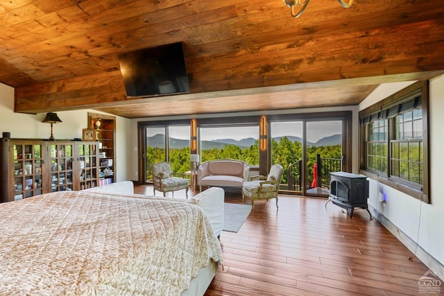 bedroom with multiple windows, wooden ceiling, wood-type flooring, and a wood stove