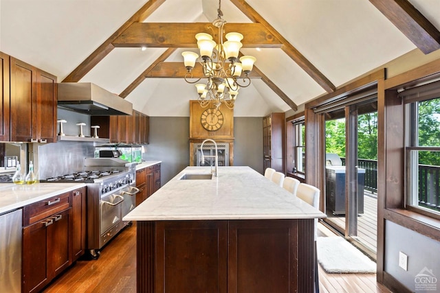 kitchen with sink, wall chimney exhaust hood, stainless steel appliances, a chandelier, and a kitchen island with sink