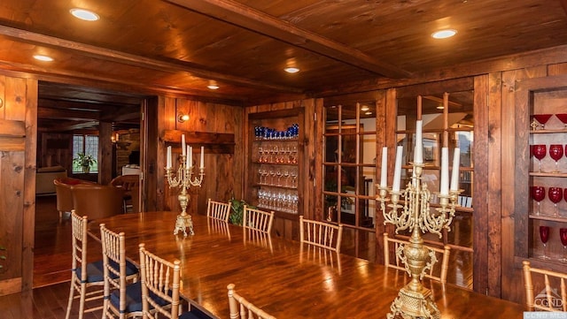 wine room with wood ceiling, wooden walls, wood-type flooring, beam ceiling, and bar area