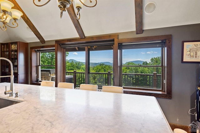 dining area with a mountain view, lofted ceiling with beams, sink, and an inviting chandelier