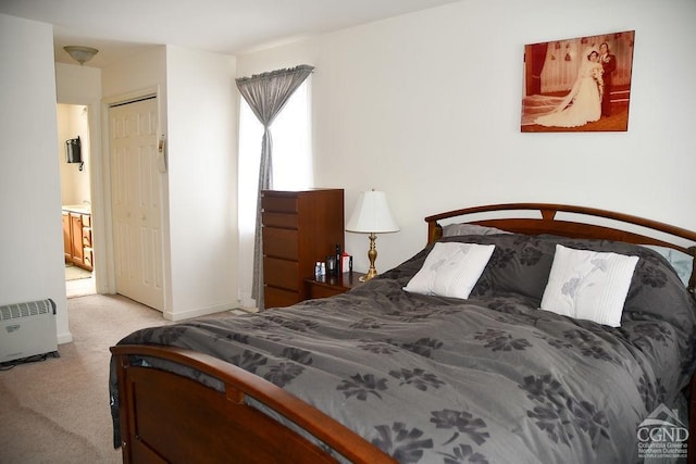 bedroom featuring light colored carpet, a closet, and ensuite bath