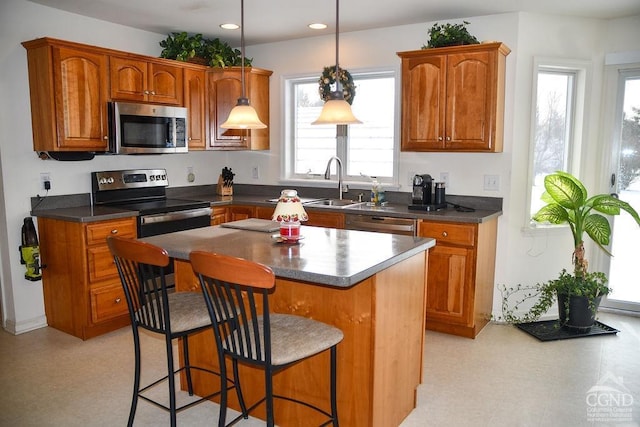 kitchen featuring a center island, a kitchen bar, appliances with stainless steel finishes, sink, and decorative light fixtures