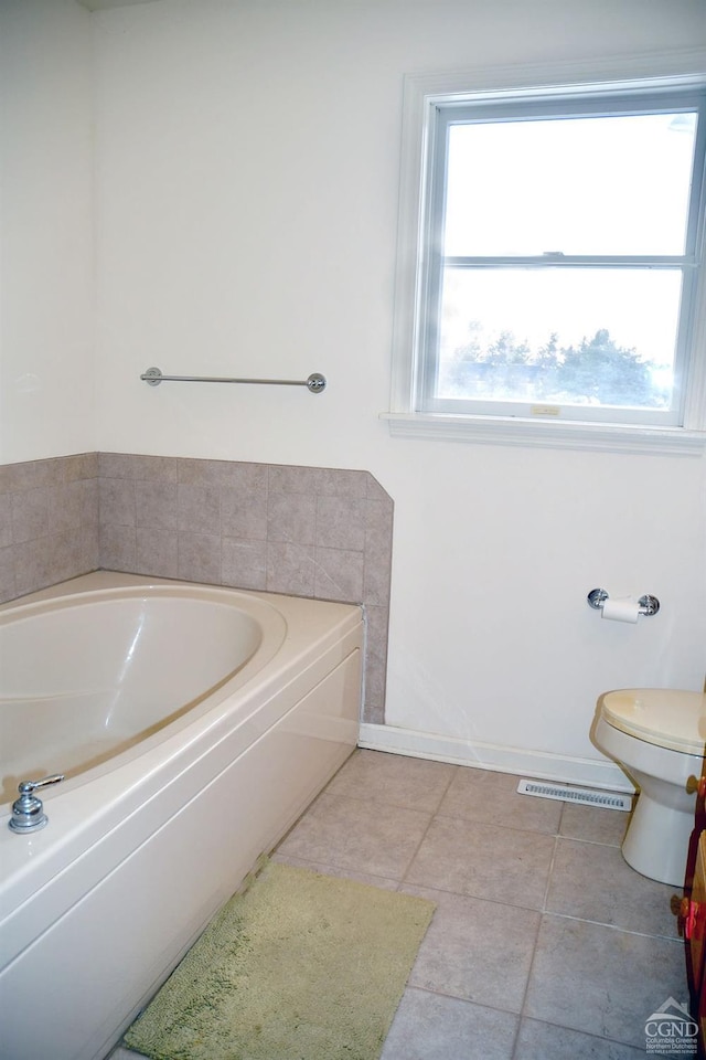 bathroom with a tub, toilet, and tile patterned floors