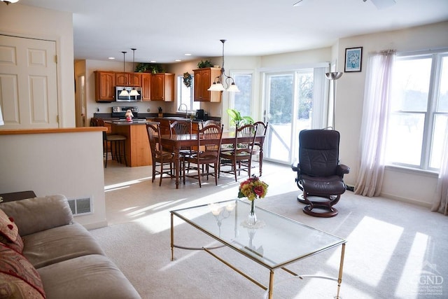 carpeted living room featuring sink and a healthy amount of sunlight