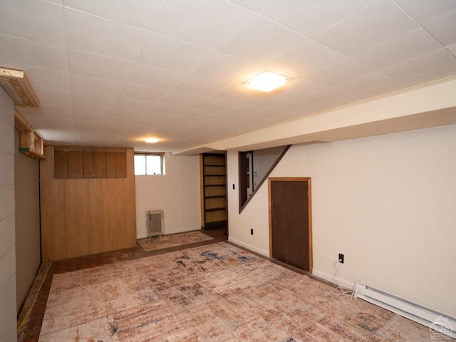 basement with baseboard heating, wooden walls, and radiator heating unit